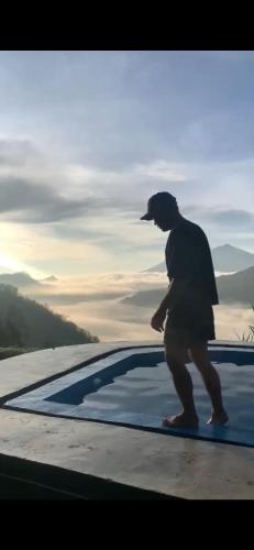a man walking next to a swimming pool at Pinggan tera glamping bali in Gretek