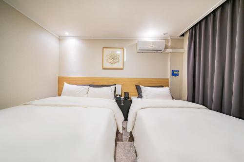 two beds in a small room with curtains at Pyeongtaek Stay Tourist Hotel in Pyeongtaek