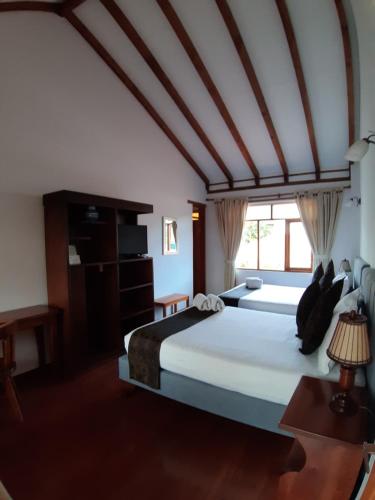 a bedroom with two beds and a large window at Hotel El Giro in Villa de Leyva