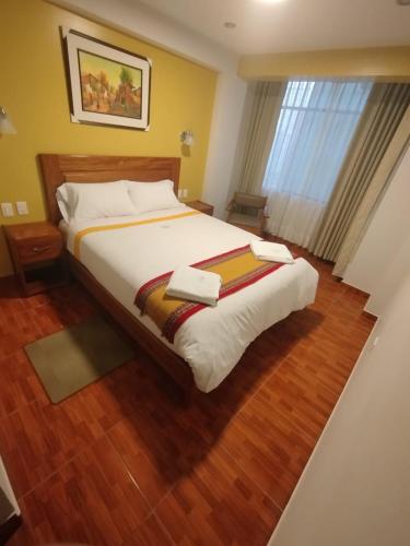 a bedroom with a large bed with wooden floors and a window at Picos House MachuPicchu in Machu Picchu