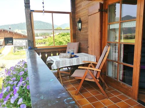 a table and a chair on the porch of a house at Gästehaus Schönfeld in Reit im Winkl
