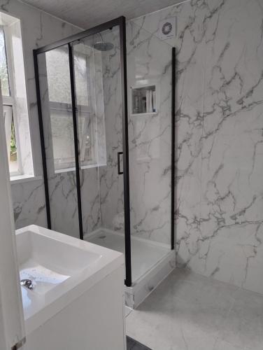 Un baño blanco con ducha y lavabo. en Mancunian Pride Villa, en Mánchester