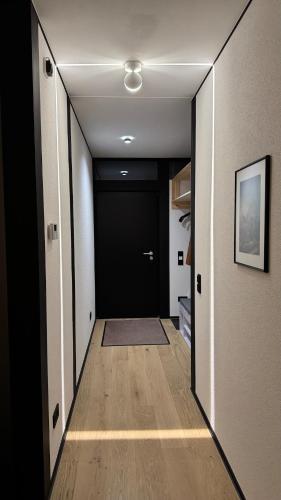 a hallway with a black door and a wooden floor at Nature Oasis near Berlin - Peaceful and Modern Stay in Falkensee