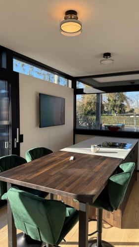 a dining room with a wooden table and green chairs at Nature Oasis near Berlin - Peaceful and Modern Stay in Falkensee
