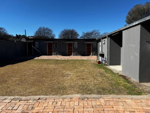 a backyard with a brick driveway and a building at Private 4 Double Room Guest Wing, Comfortable, Secure Parking, Wi-Fi, Ensuite Bath in Ermelo