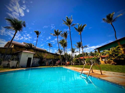 a blue swimming pool with palm trees in the background at Casa Mandacaru Pousada in Caucaia