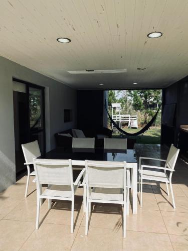 a dining room with a table and white chairs at Casa de campo, paz, tranquilidad in Concordia