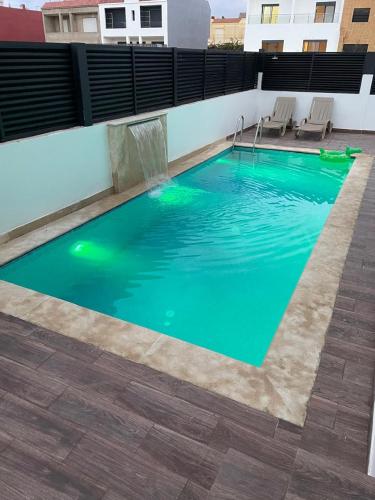 a pool on the roof of a building with green water at Villa Chez Badre with Pool High Standing in Sidi Rahal