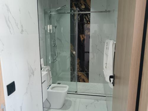 a bathroom with a toilet and a glass shower at Villa Chez Badre with Pool High Standing in Sidi Rahal