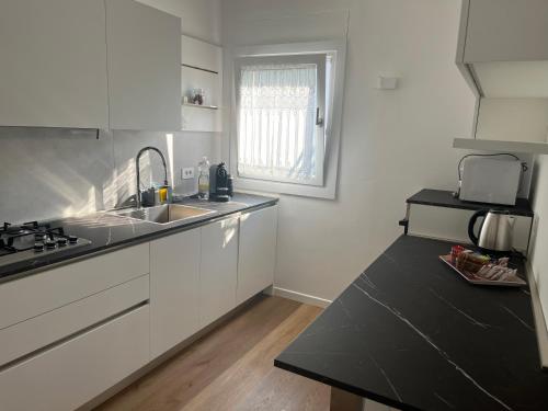 a kitchen with white cabinets and a sink and a window at Casa Inès in Conegliano