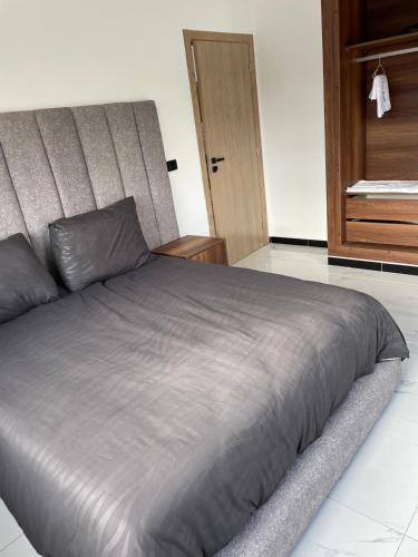 a large bed in a bedroom with a wooden door at Villa Chez Badre with Pool High Standing in Sidi Rahal