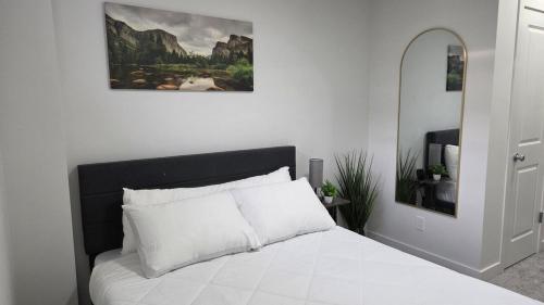 a bedroom with a white bed with a picture on the wall at Modern 2BR near Hospital, YMCA, Stores in Calgary