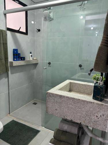a bathroom with a glass shower with a sink at Lorenna Reservas in Araxá