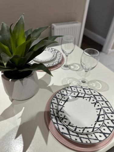 a table with plates and glasses and a potted plant at Charming Home Nottingham City in Lace Market Free parking in Nottingham