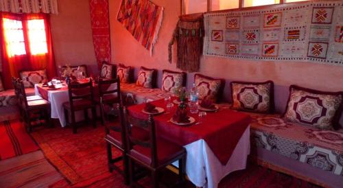 une salle à manger avec des tables, des chaises et un tissu de table rouge dans l'établissement Maison d'Hôte Valentine, à Tinghir