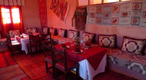 a dining room with tables and chairs with red table cloth at Maison d'Hôte Valentine in Tinerhir