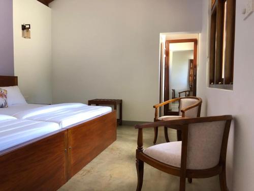 a bedroom with a bed and a chair and a mirror at PEKOE VALLEY Huluganga in Huluganga