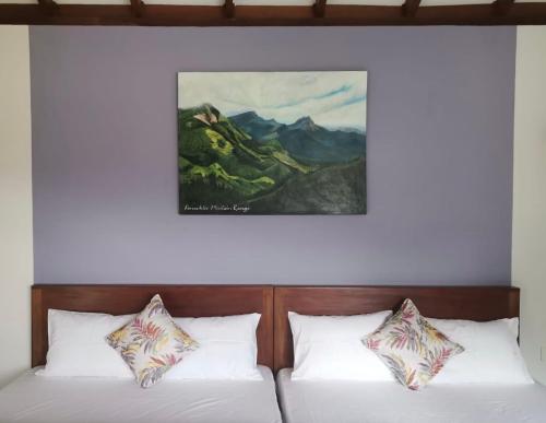 two beds in a room with a painting on the wall at PEKOE VALLEY Huluganga in Huluganga