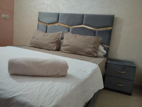 a bed with a blue headboard and a white blanket and pillows at jardaine d'Ifrane in Ifrane
