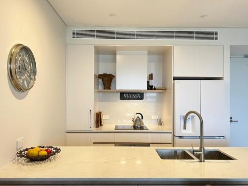 a kitchen with a sink and a bowl of fruit on a counter at Mia Mia at the Marina in Shellharbour