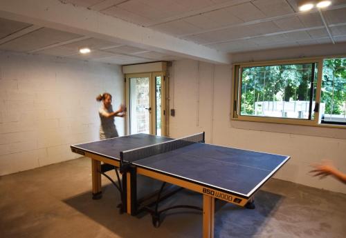 a woman standing in a room with a ping pong table at Maison d'architecte sur Seine in Issy-les-Moulineaux