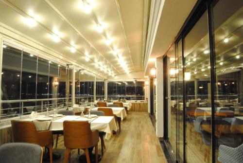 a restaurant with white tables and chairs and windows at Panaroma Damla Otel in Samsun