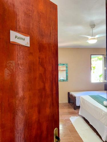 a room with a bed and a door with a sign on it at Casa Mandacaru Pousada in Caucaia