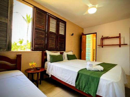 a bedroom with two beds and two windows at Casa Mandacaru Pousada in Caucaia
