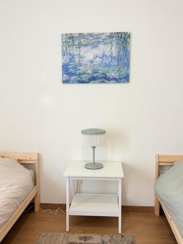 a white table with a lamp on it next to two beds at Côté Parc - appt entier neuf et cosy, parking & au pied du métro à Lyon in Vénissieux