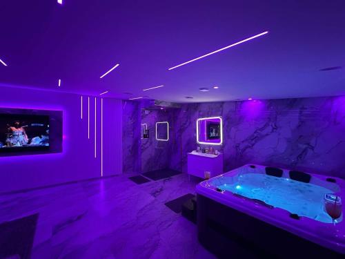 a purple room with a tub and a tv at Beautys Spa in Lens