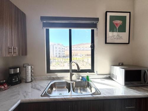 a kitchen counter with a sink and a window at Vinedos del Mar 2BR 2BA with pool in Ensenada