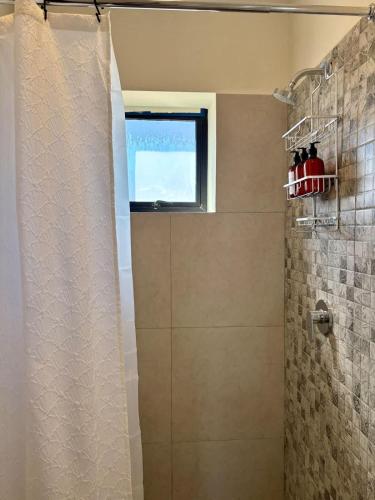 a shower with a glass door and a window at Vinedos del Mar 2BR 2BA with pool in Ensenada
