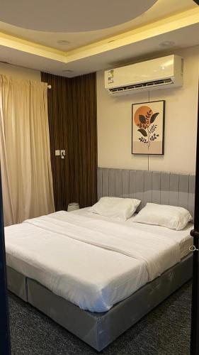 a bedroom with a large bed with white sheets at شقة بصالة وغرفة نوم حديثة جازان in Jazan