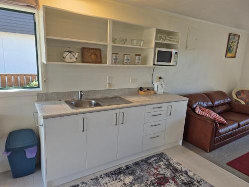 a kitchen with a sink and a couch in a room at Blue Marlin Apartments in Whitianga