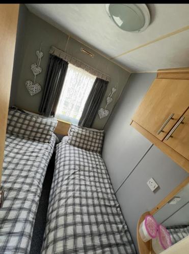 two beds in a small room with a window at Kings Caravan Park A-56 in Chapel Saint Leonards