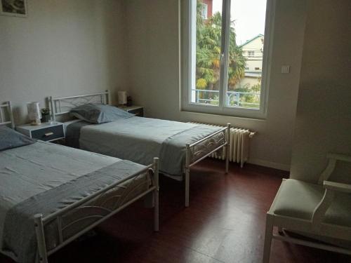a room with two beds and a window at Maison du Sacre-Coeur in Lourdes