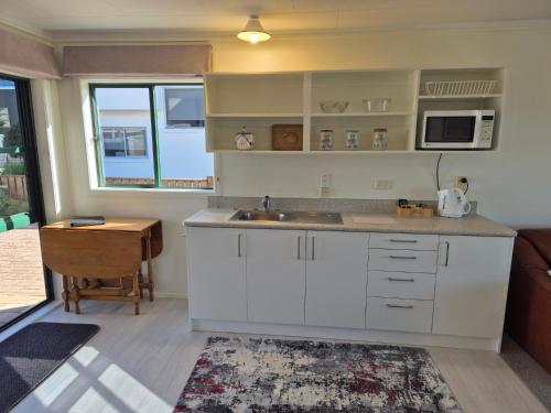 a kitchen with white cabinets and a sink and a table at Blue Marlin Apartments in Whitianga