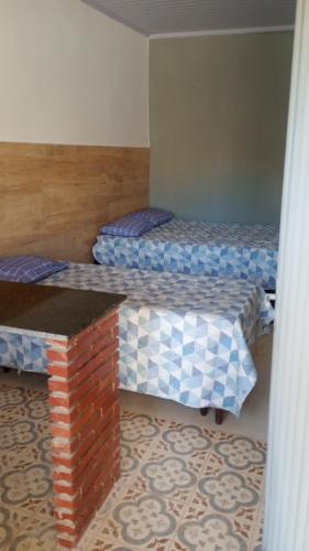 a room with two beds and a brick wall at Hospedaria Km 20 da Br 040 Luziânia in Luziânia