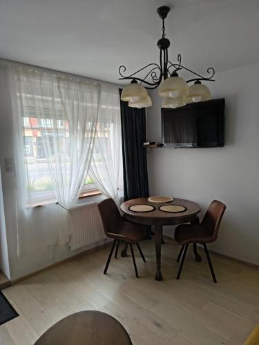 a dining room with a table and chairs and a window at Apartamenty Stara Cegła in Zgorzelec