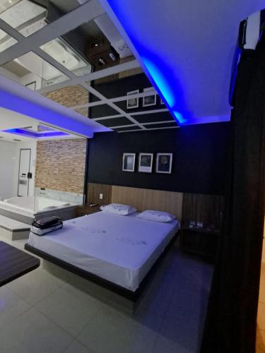 a bedroom with a large bed with a blue lighting at Motel Lunary in Piedade