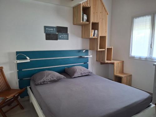 a bedroom with a bed with a blue headboard and a chair at Appartement neuf a 150 metres de la mer wifi in Le Diamant