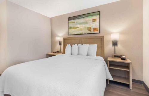 a hotel room with a white bed and two night stands at Extended Stay America Suites - Orange County - Anaheim Convention Center in Anaheim