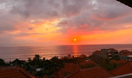 ein Sonnenuntergang über dem Meer mit Häusern und Gebäuden in der Unterkunft Pooja Ocean View Cottage in Nusa Penida