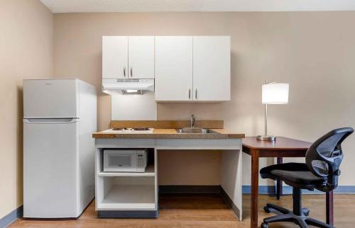 a kitchen with a refrigerator and a desk with a microwave at Extended Stay America Suites - Indianapolis - Airport - W Southern Ave in Indianapolis