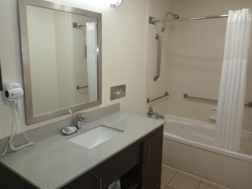 a bathroom with a sink and a mirror and a tub at Best Western Garden Inn in San Antonio