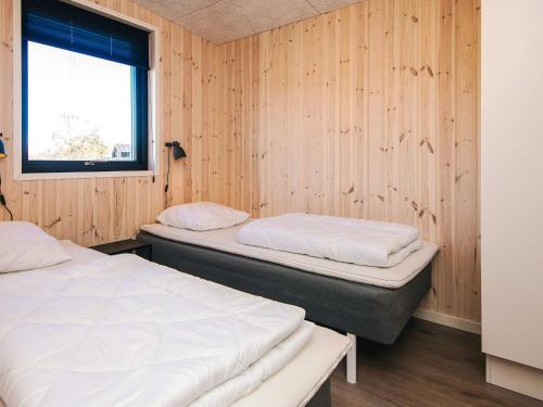 two beds in a room with wooden walls at 5 star holiday home in Grenaa in Brøndstrup