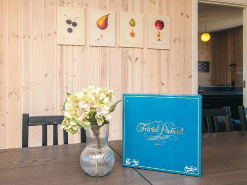 a book sitting on a table next to a vase with flowers at 5 star holiday home in Grenaa in Brøndstrup