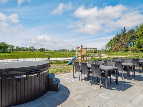 a patio with a table and chairs and a playground at 5 star holiday home in Grenaa in Brøndstrup