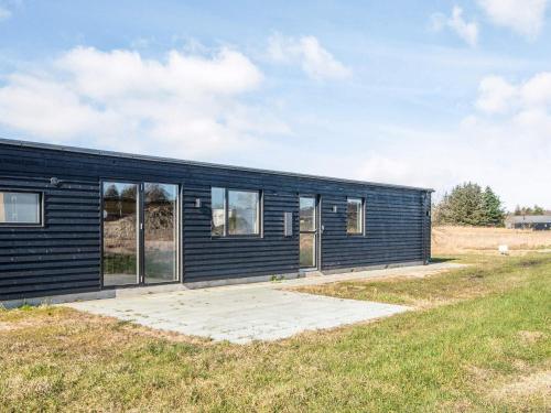 a black house with windows on a field at 5 star holiday home in Grenaa in Brøndstrup