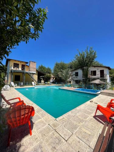 a swimming pool with two red chairs next to it at Santa Rosa Cabañas in Santa Rosa de Calamuchita